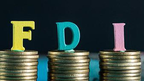 Colorful letters "F," "D," and "I" stand on stacked gold coins against a dark background, symbolizing Foreign Direct Investment.