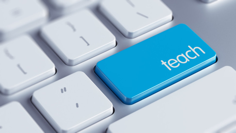 A close-up of a keyboard with a prominent blue key labeled "teach."