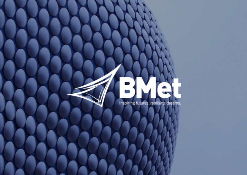 A close-up of a textured, circular surface with a glossy blue hue, featuring the BMet logo and the tagline "Inspiring futures, realising dreams."