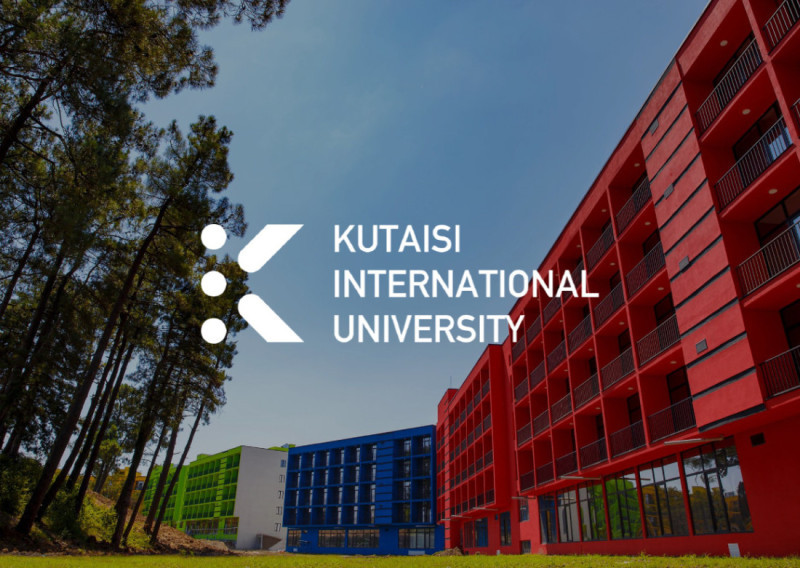 Colorful buildings of Kutaisi International University are set against a clear blue sky, surrounded by tall pine trees. The university's logo is prominently displayed in the foreground.