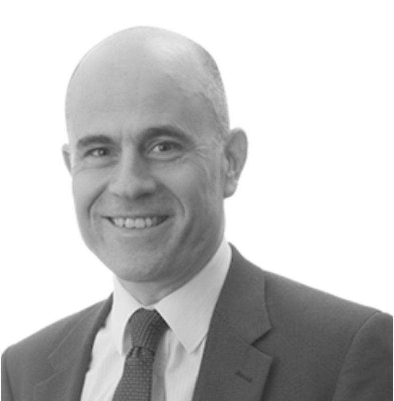 A smiling man with a bald head, wearing a suit and tie, poses against a plain white background.