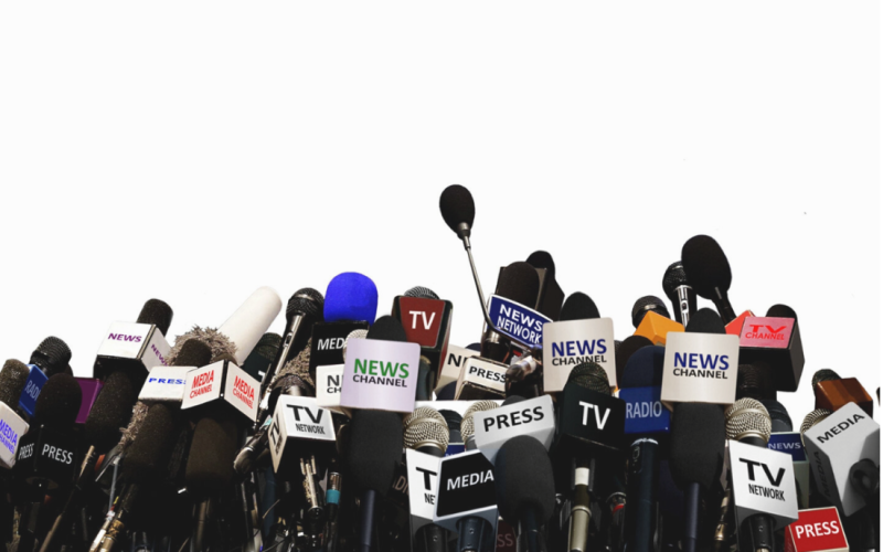 A cluster of various microphones and press badges from different news organizations, set against a white background.