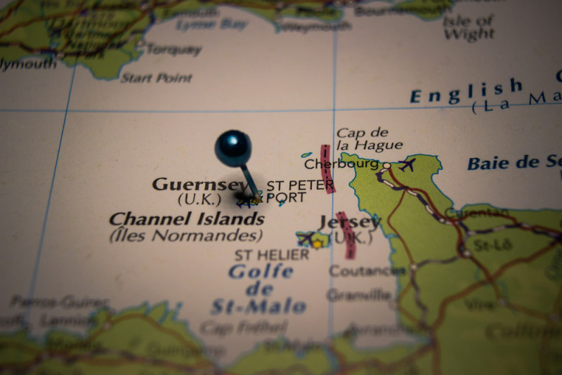 A close-up of a map highlighting the Channel Islands, specifically Guernsey and Jersey, with a blue pin marking St. Peter Port.