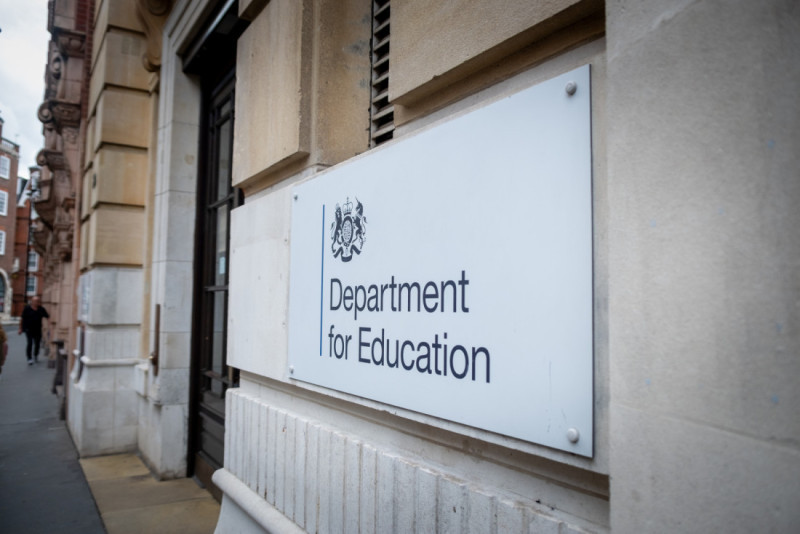 Sign for the Department for Education mounted on a building's facade, featuring a coat of arms and clear lettering.