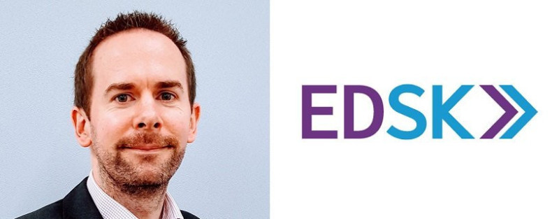 A man with short brown hair and a light beard smiles, wearing a suit. Next to him is the logo for EDSK, featuring the letters "EDSK" in purple and blue.