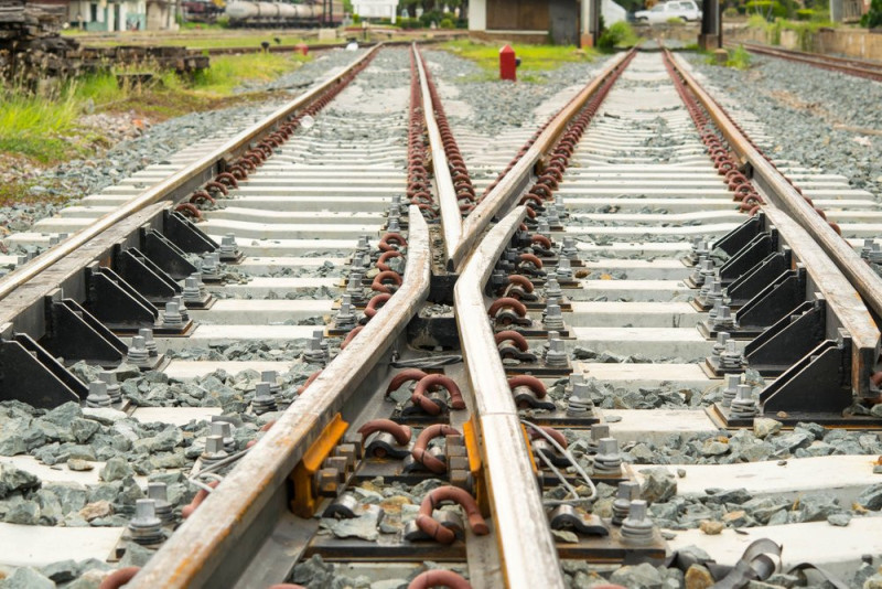 Railway tracks diverging at a switch with gravel and fastening elements visible.